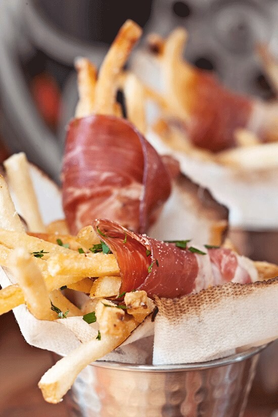 Foto de batatas fritas enroladas em finas fatias de embutidos