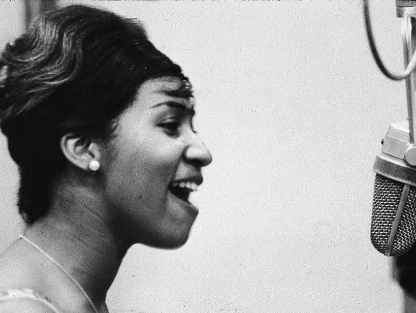 Foto em preto e branco de Aretha Franklin gravando em estúdio