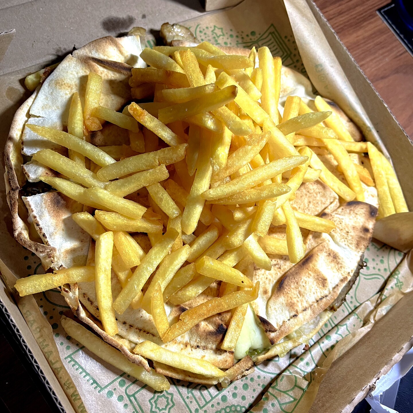 Uma pilha de batatas fritas sobre um sanduíche de tele-entrega