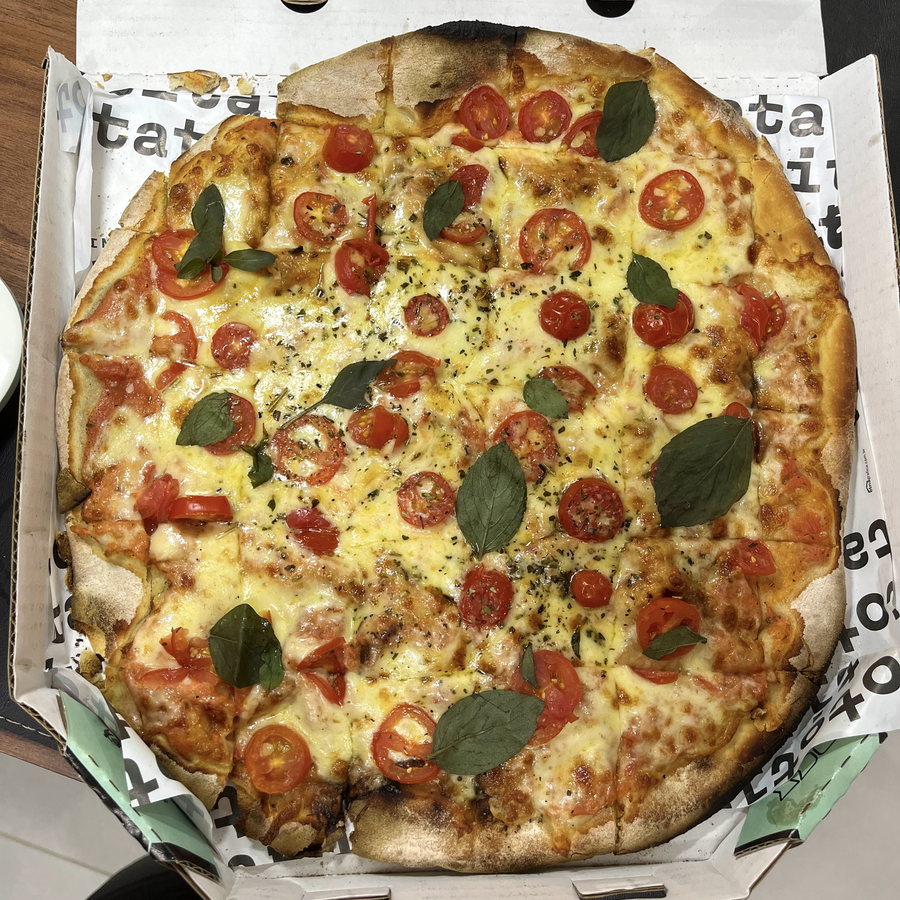 Uma pizza marguerita da pizzaria do vizinho, cortada em quadradinhos para aperitivo