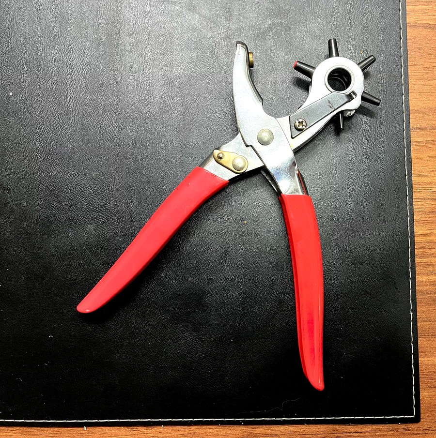 Um alicate especial, com manoplas vermelhas, sobre um protetor de mesa em cor preta