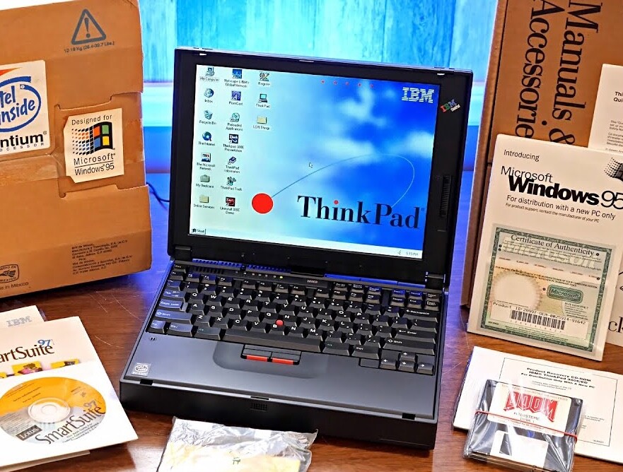Um ThinkPad 380 entre vários disquetes e CDs de instalação