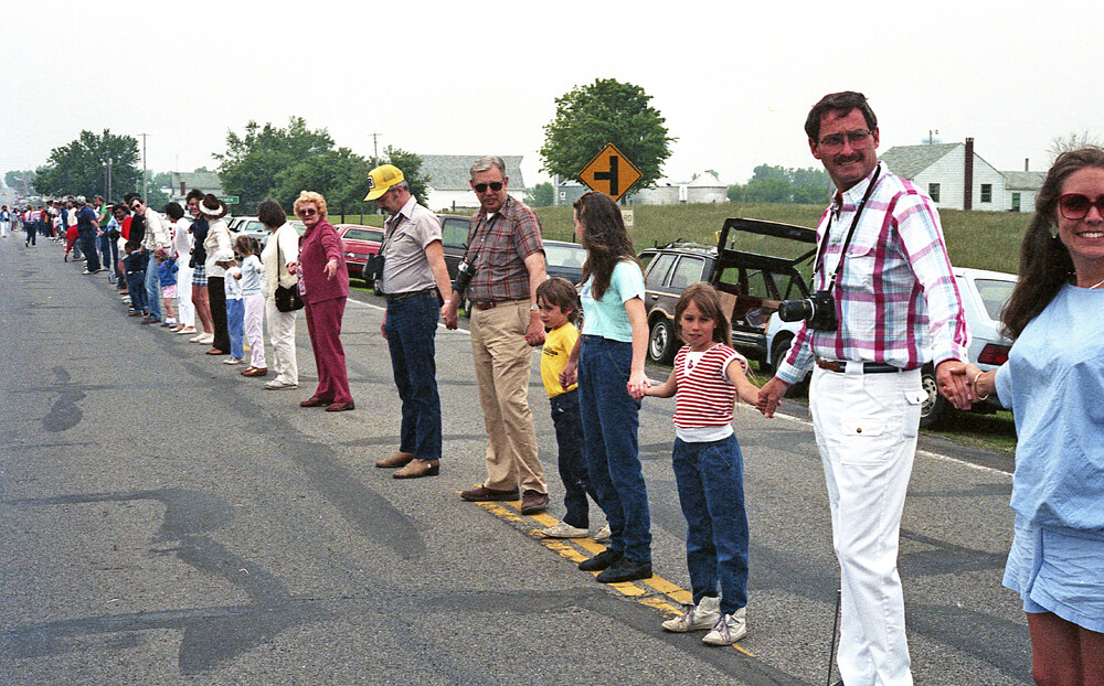 Várias pessoas de mãos dadas no meio da rua