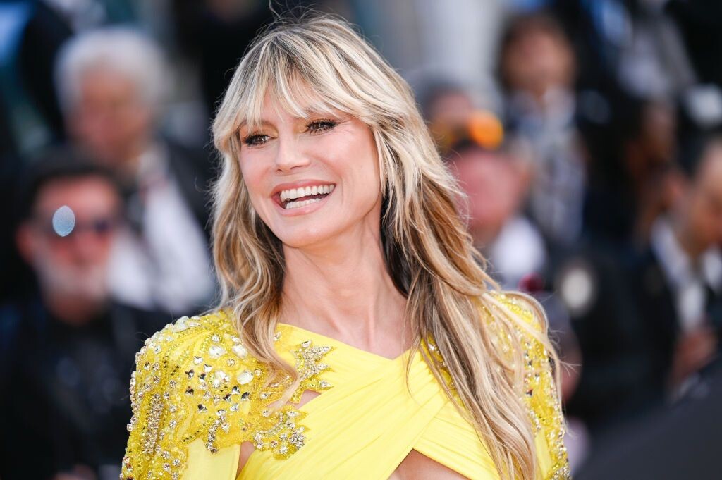 Heidi Klum sorrindo, de vestido amarelo