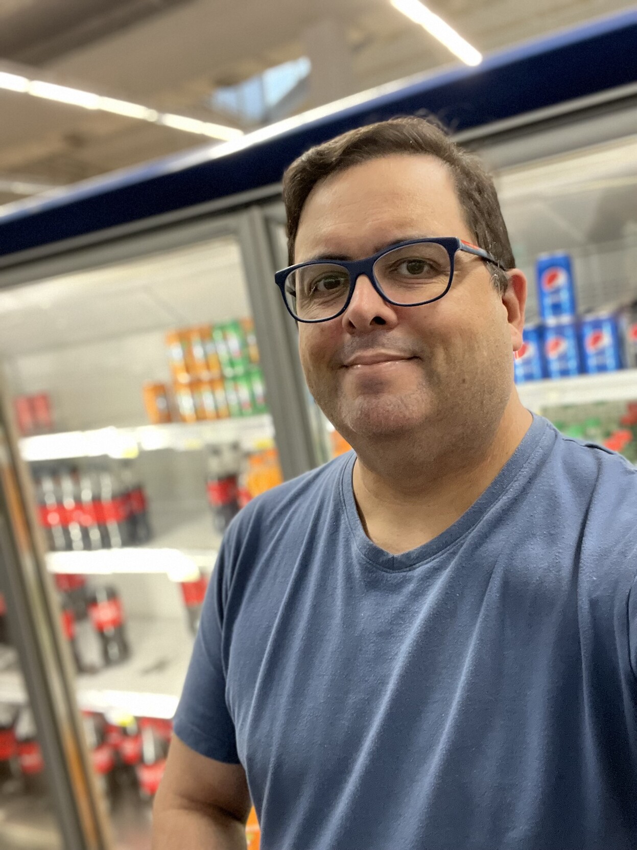 Selfie de camiseta azul bem confortável em frente ao balcão refrigerado do mercado