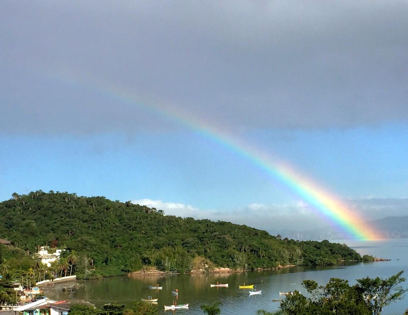 Portinho dos pescadores no Bairro João Paulo, onde hoje tem um trapiche público, com várias embarcações fundeadas, e um arco-íris visível em frente à costa de São José, no continente.