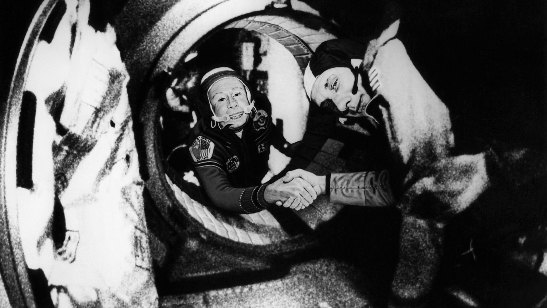 O comandante da tripulação soviética da Soyuz, Alexei Leonov, à esquerda, e o comandante da tripulação americana da Apollo, Thomas Stafford apertam as mãos no espaço depois que as espaçonaves Apollo e Soyuz acoplaram em 17 de julho de 1975