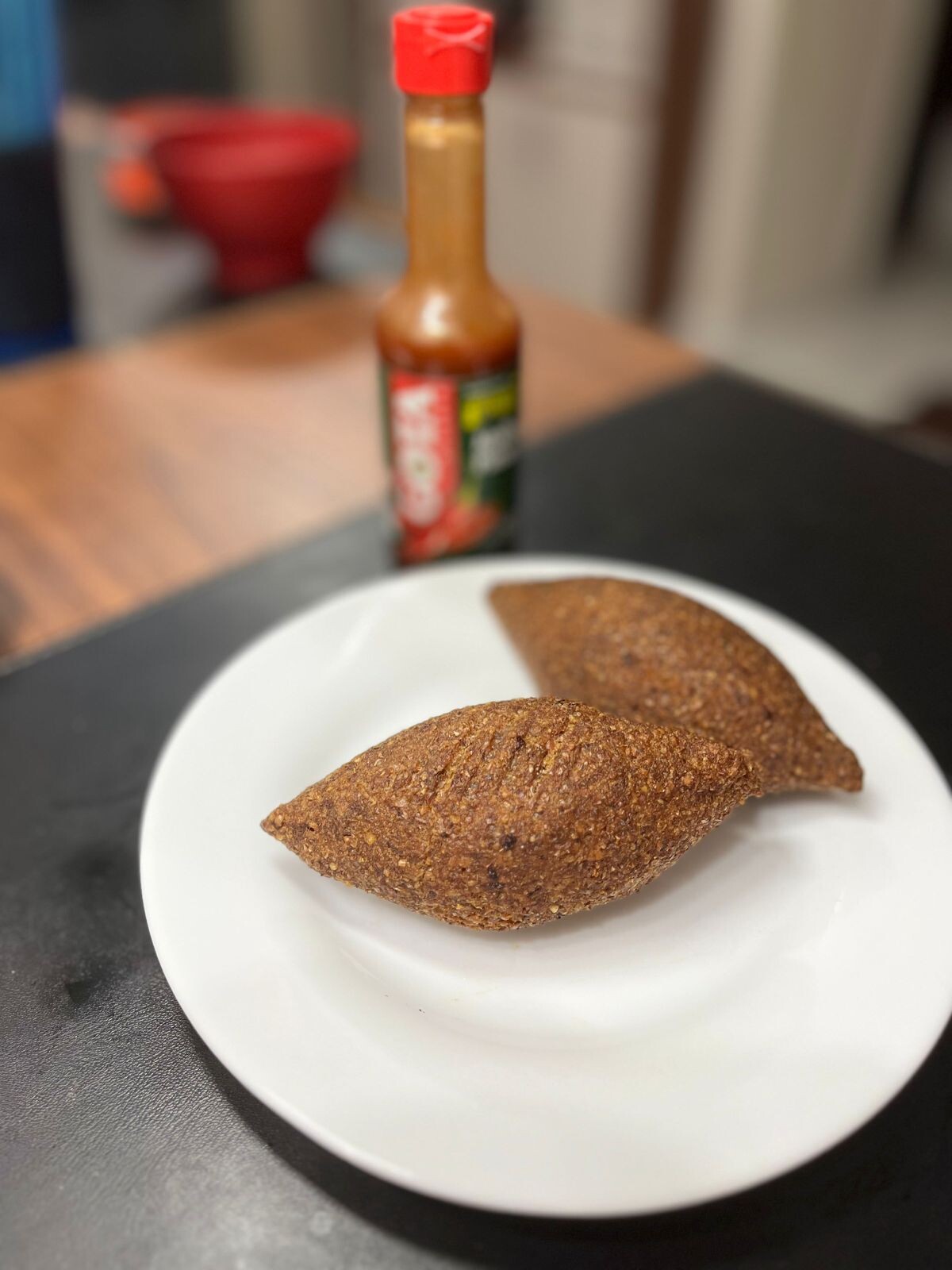 2 kibes num pratinho branco, e um molho de pimenta marca Gota ao fundo