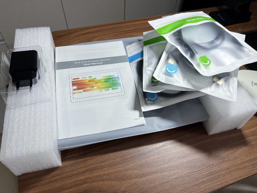 Um equipamento de informática ainda semi-embalado, sobre a bancada, com cabos e impressos espalhados sobre ele