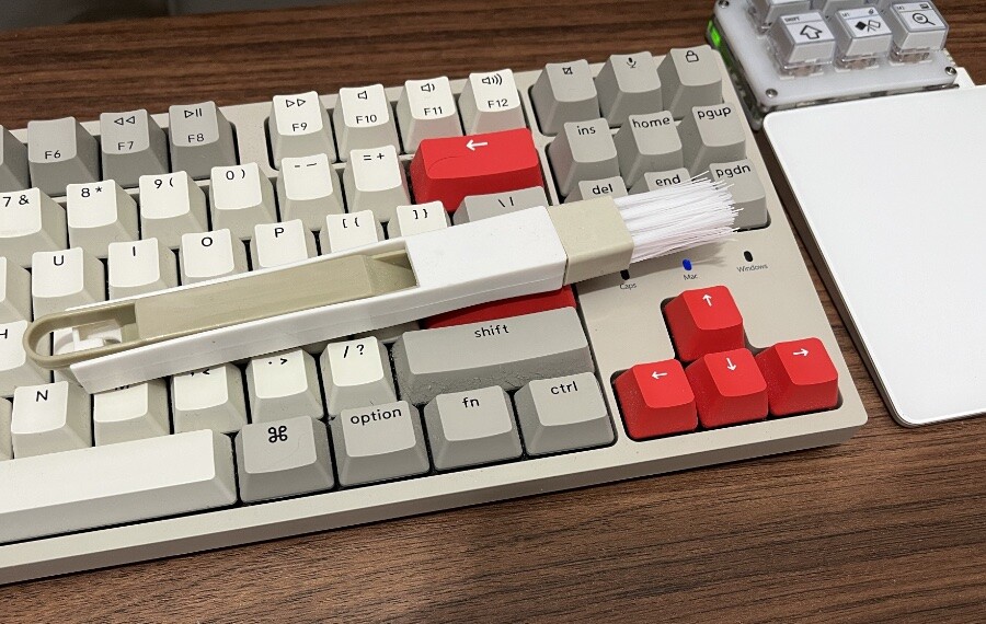 uma escova de limpar teclados, posicionada sobre um teclado