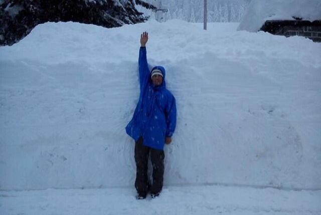 Pessoa com braço lavantado junto a dois metros de neve acumulada, em foto moderna