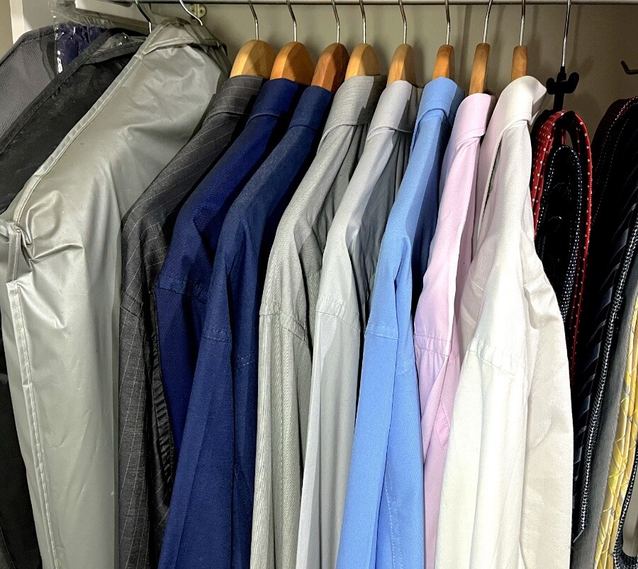 Cabides com 2 paletós (encapados), e 8 camisas sociais, em ordem cromática (do cinza escuro, passando por azuis e rosa, ao branco), e gravateiro