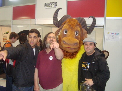 O GNU mascote do FISL, ao lado do dançarino folk Richard Stallman, em frente ao stand da FSFLA num FISL