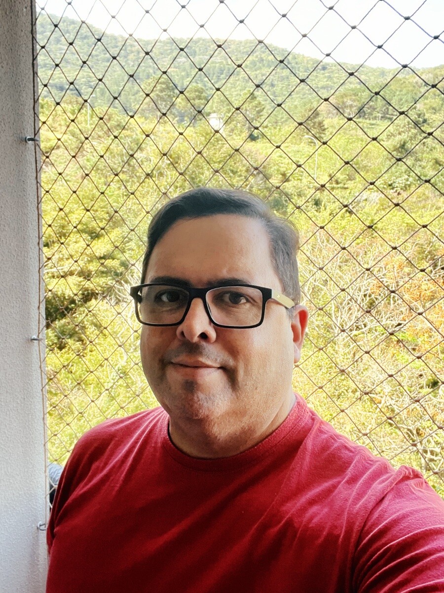 selfie minha, na sacada, de óculos novo e camiseta vermelha antigona