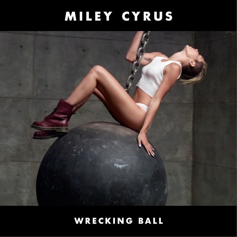 Banner do single de Wrecking Ball, com Miley de calcinha e top brancos, e botas, posicionada sobre uma bola de demolição, cuja corrente ela segura com a mão direita e as pernas.