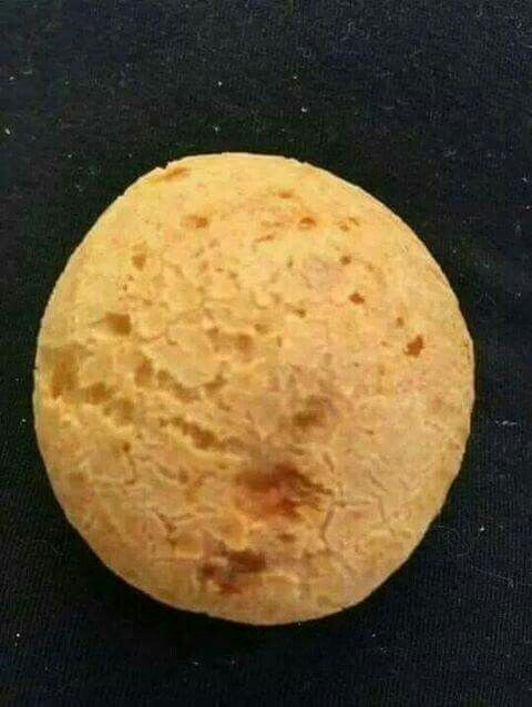 Foto de um pão de queijo sobre uma toalha escura