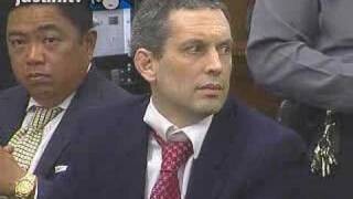 Hans Reiser no tribunal, com as roupas em desalinho e expressão tensa. Atrás dele, um policial penal.