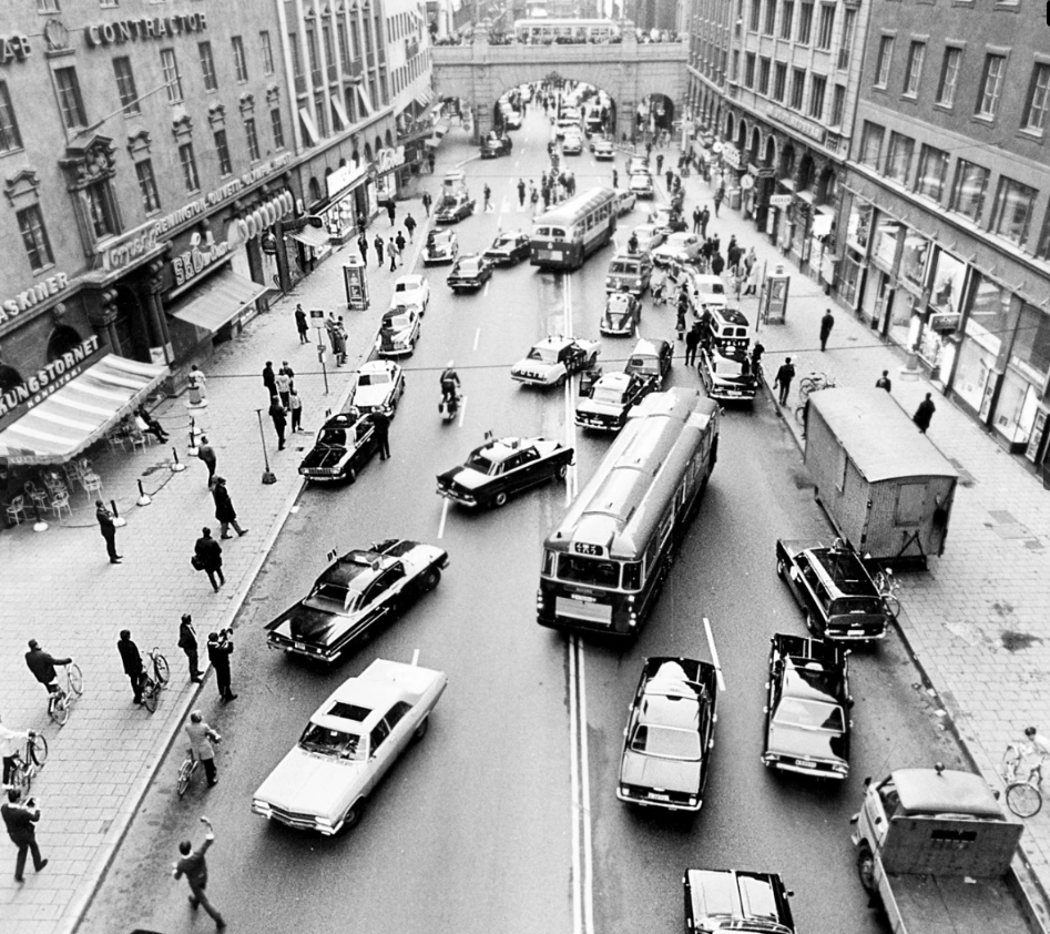 Foto em preto e branco de carros e ônibus em confusão de tráfego em trecho urbano da Suécia 