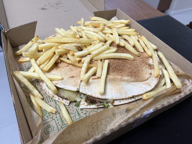 Um beirute de rosbife com adicional de fritas, na caixa da tele-entrega