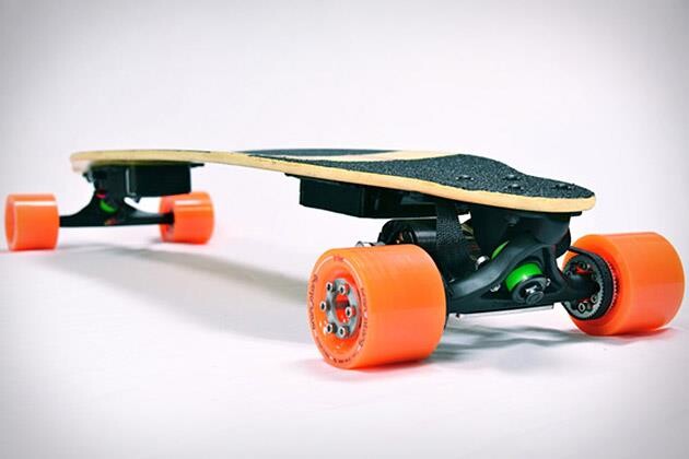 Um skate longboard elétrico, visto ao nível do chão, com os motores instalados junto aos trucks, e rodas em cor laranja