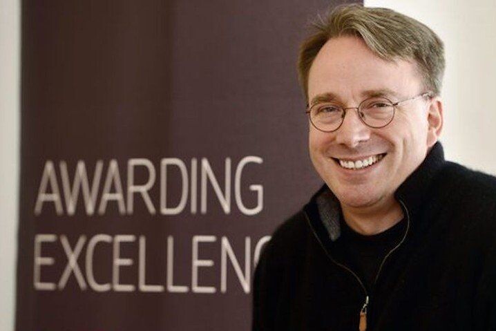 Linus Torvalds sorri para câmera. No cenário, está escrito Awarding Excellence