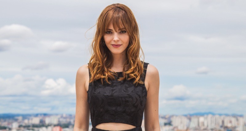 Titi Müller, de preto, com céu e paisagem urbana ao fundo, em foto de Rachel Lira