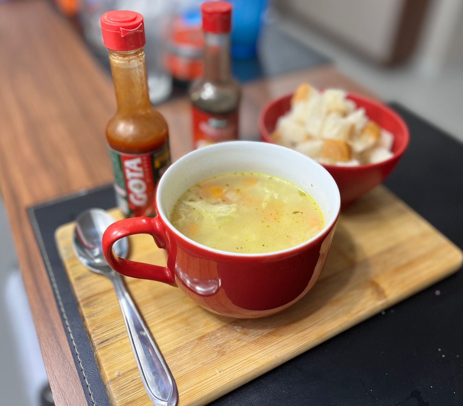 Mesa servida com uma sopa, colher, um pote com cubinhos de pão que eu cortei, e molhos inglês e de pimenta