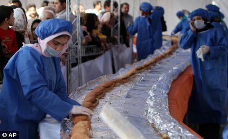 Em meio à multidão, iranianas paramentadas preparam o sanduíche