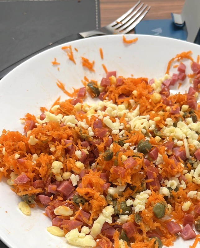 Um prato de recheio de queijo ralado, linguiça picada, cenoura ralada e condimentos