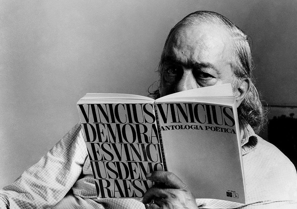 VInicius de Moraes posa para foto em preto e branco lendo a sua própria Antologia Poética