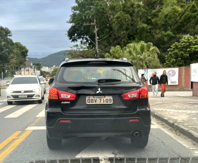 Carro escuro trafegando com placa OBV-xxxx