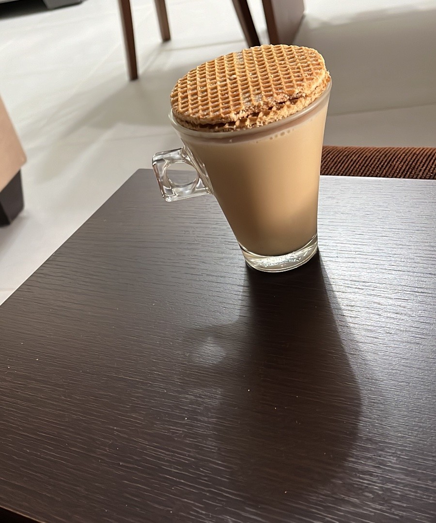 Xícara de café com leite, com dois biscoitos tipo stroopwafel empilhados sobre ela