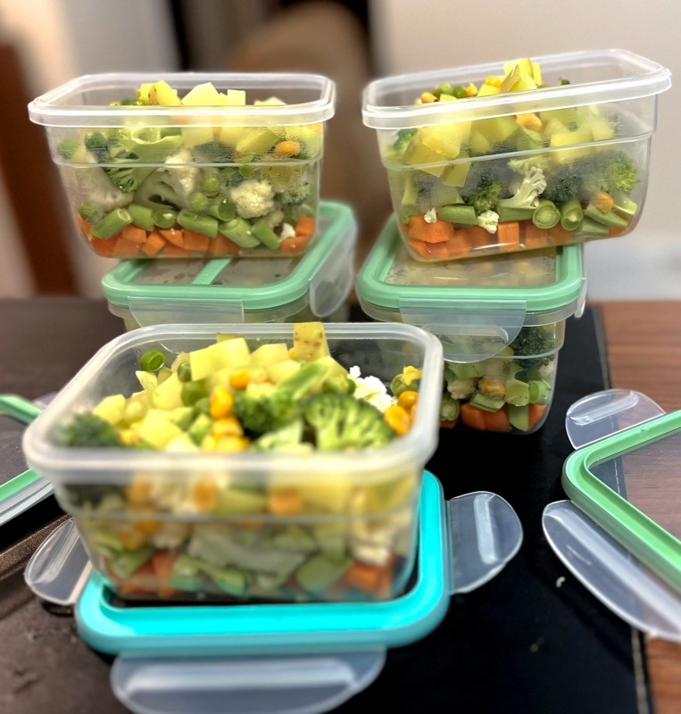 5 embalagens herméticas contendo legumes picados: cenoura, vagem, couve-flor, brócolis e batata, além de milho e ervilha. Os 4 primeiros itens são crus.