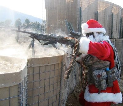 Homem opera uma metralhadora, em meio à fumaça de tiros, com uma roupa de papai noel por baixo de seu traje de combate