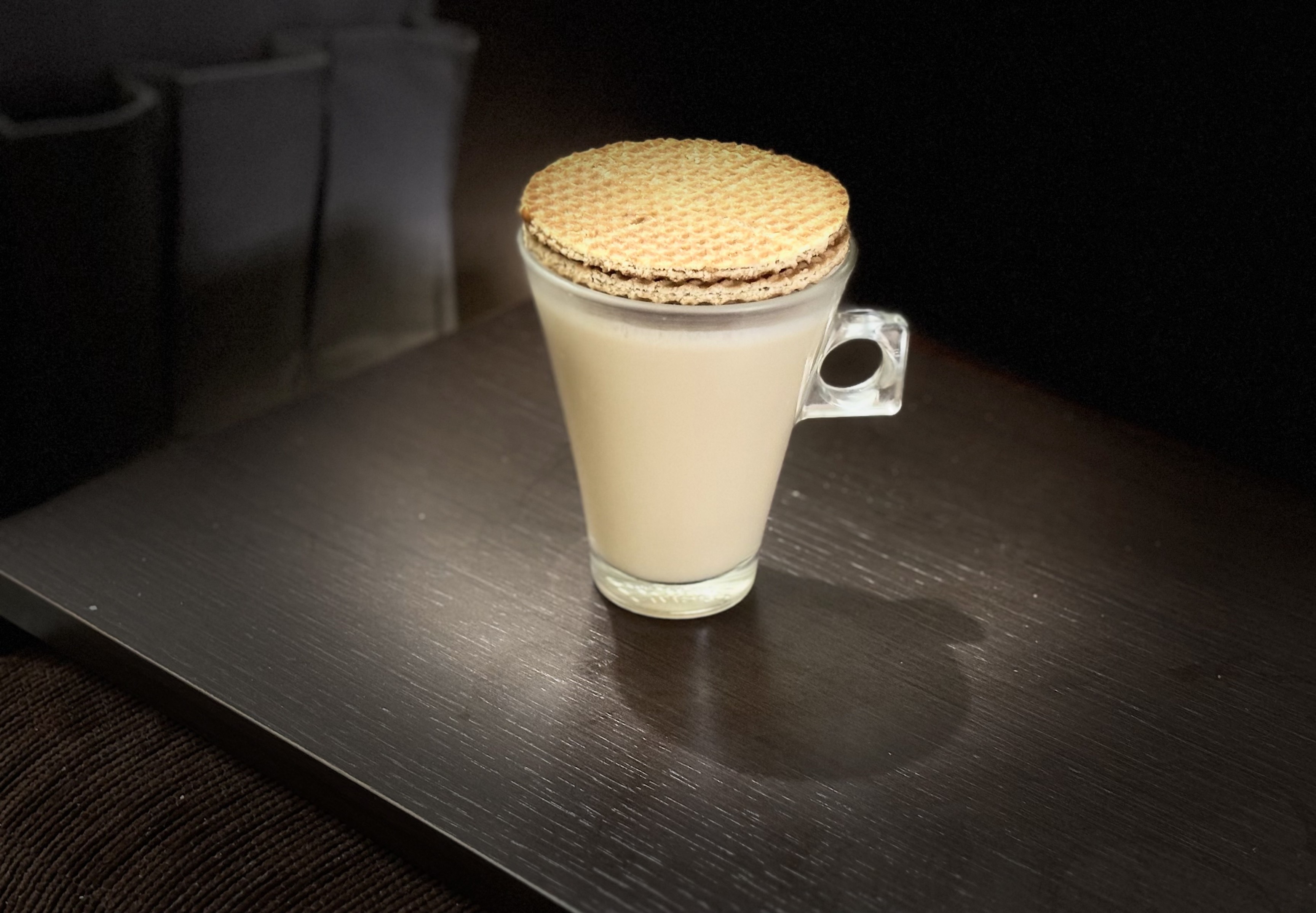 Xícara de café com leite tampada por 2 biscoitos stroopwafel empilhados