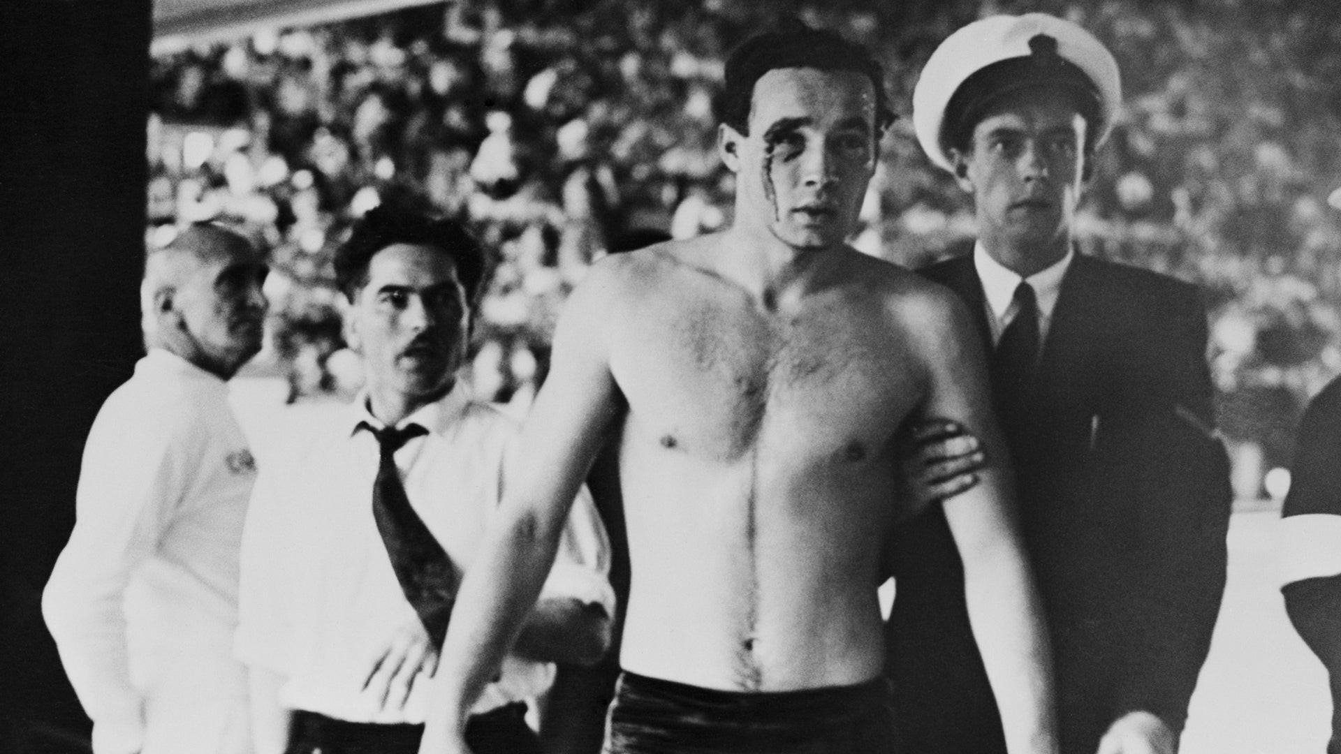 Já fora da piscina, um dos húngaros, ferido e com sangue escorrendo da região próxima aos olhos, é escoltado 