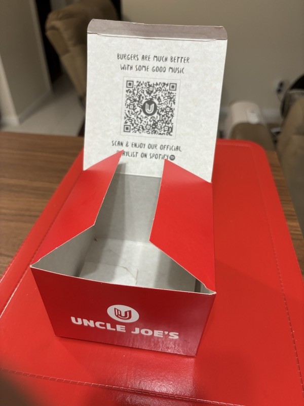 Caixa de hambúrguer do tio joão, com qr code impresso levando para uma playlist oficial da lanchonete