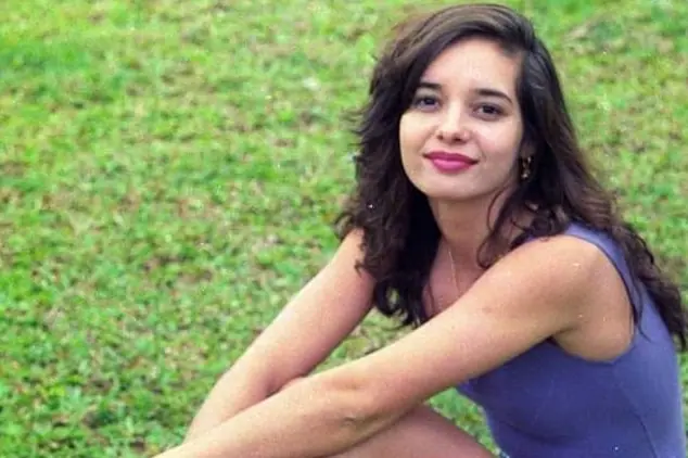 Daniela, sentada na grama, sorri para a câmera
