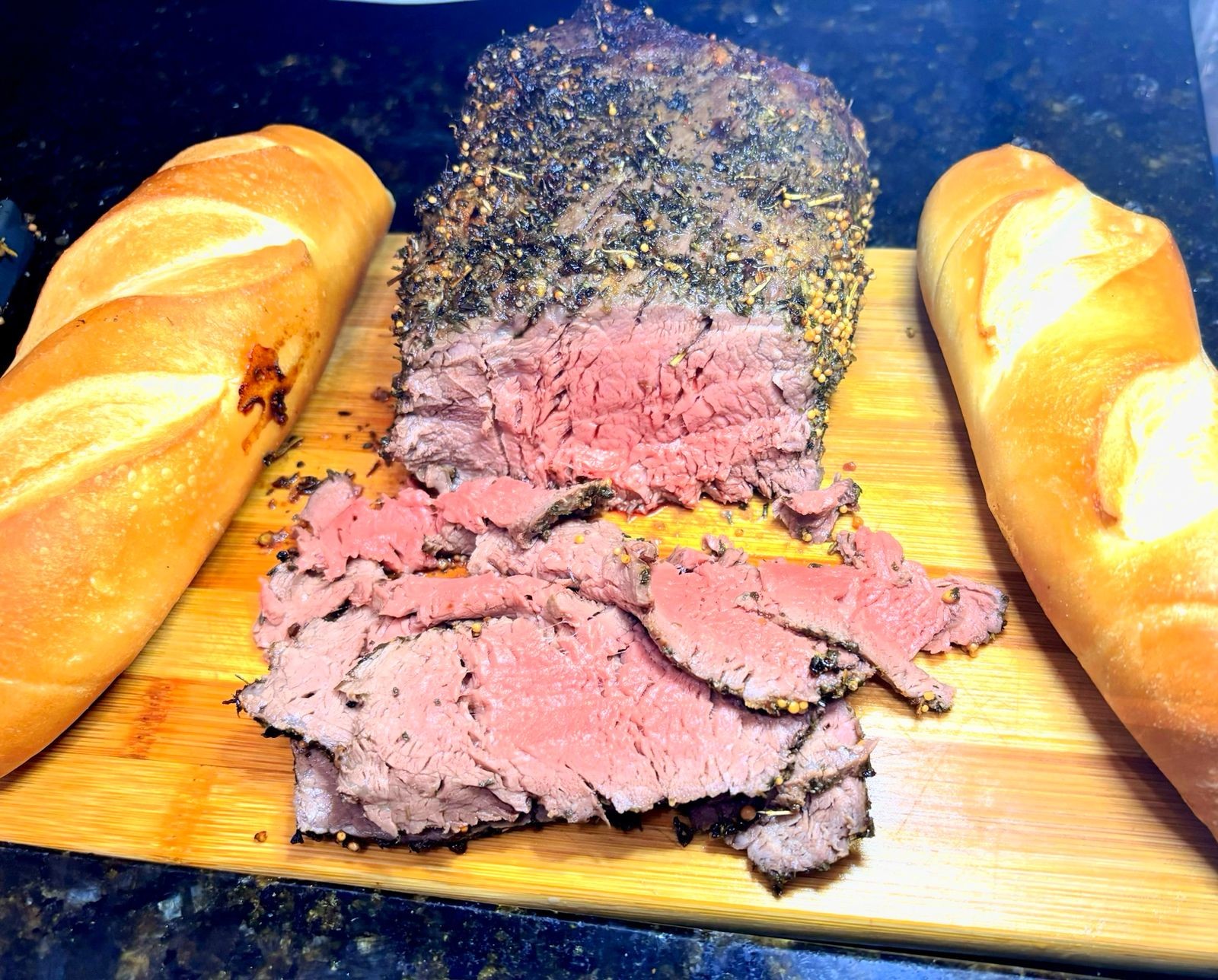 Rosbife com crosta de especiarias e mostarda em grãos, parcialmente fatiado, entre dois pães