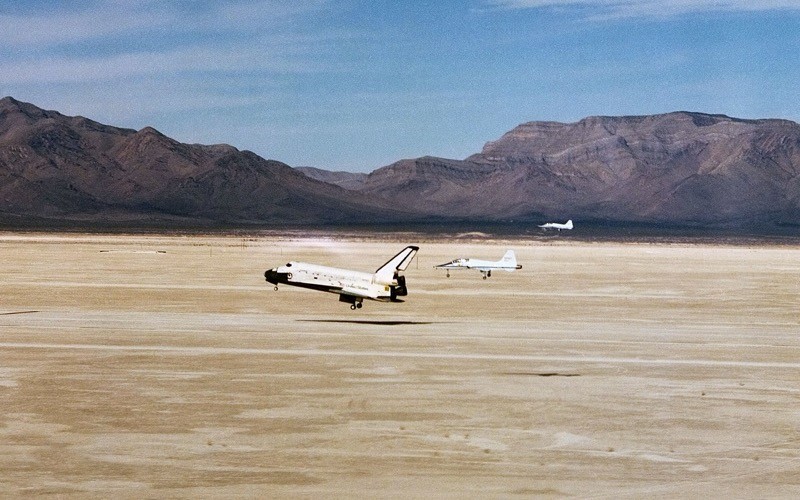 O ônibus espacial Columbia em foto a segundos do pouso, com dois aviões de escolta T-38 seguindo-o até a pista, após a conclusão da missão STS-3.
