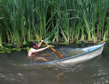 um homem motivado remando em um barco quase completamente abaixo da linha da superfície da água