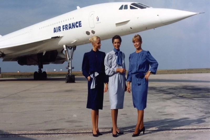 Três comissárias uniformizadas posam na pista em frente a um Concorde da Air France