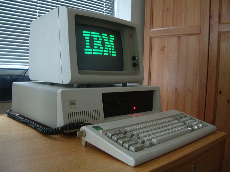 IBM PC XT exibindo a palavra IBM em letras grandes na tela monocromática de fósforo verde, e com o HD de 10MB original, que ocupava duas baias verticais de 5¼.<br>