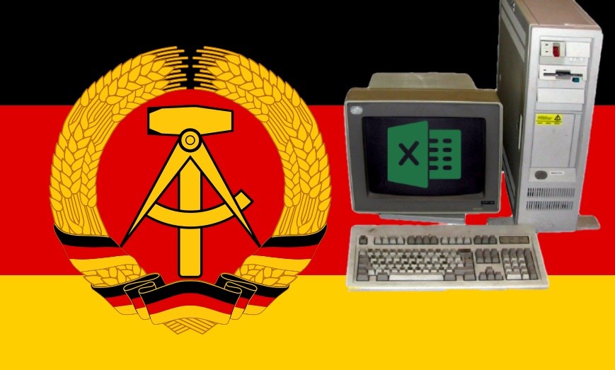 Um computador IBM PS/2 Modelo 80, exibindo na tela um ícone do Excel, sobre uma bandeira da Alemanha Oriental.