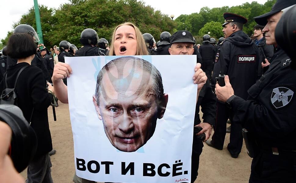 Foto de manifestante segurando cartaz com imagem de Putin