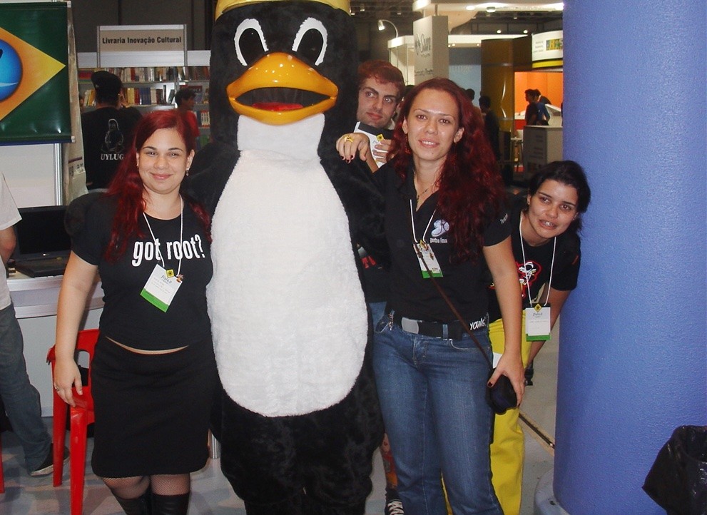 Integrantes das LinuxChix em um FISL, posando com o Tux.<br>
