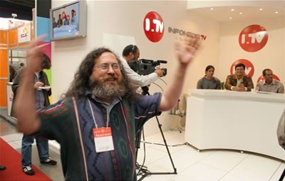 Richard Stallman agita os braços em frente ao stand da Infomedia TV durante a participação da Microsoft no FISL.