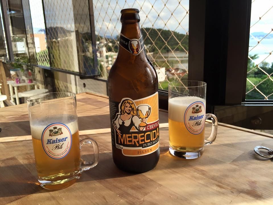 Na mesa da sacada, dois canecos já servidos e uma cerveja Merecida Pilsen, vinda da minha terra natal