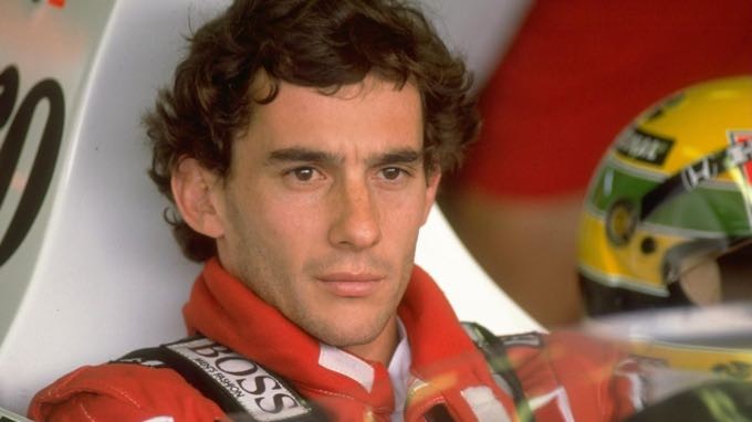 Ayrton Senna, no cockpit e ao lado do seu capacete amarelo.