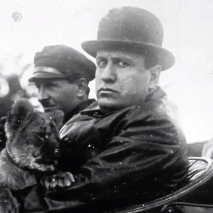Foto em preto e branco de um cãozinho em má companhia, no colo de Mussolini e ao lado de Hitler